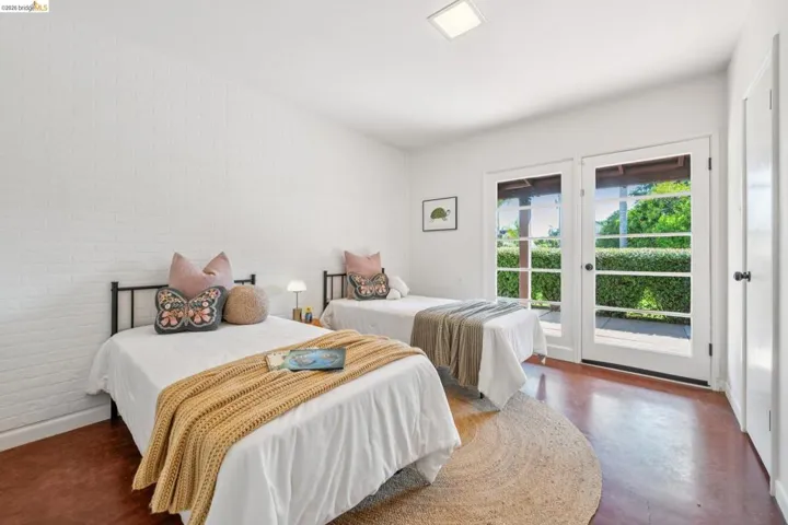 Room featuring white painted brick walls, rich reddish-brown flooring, and bright white trim