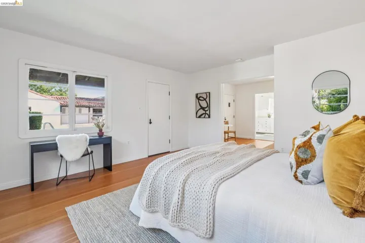 Bright room featuring wood-finish flooring, white walls, and a large multi-pane window
