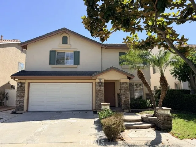 This attractive two-story residence features charming curb appeal with a warm, neutral exterior, classic shutters, and a spacious two-car attached garage. The professionally landscaped front yard showcases mature palm trees, decorative rock accents, and drought-tolerant plantings for low-maintenance beauty. A welcoming front entry is framed by lush greenery, while the wide driveway provides additional parking. The well-maintained exterior and inviting streetscape create an excellent first impression, ref...