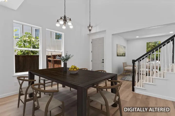 Dining area featuring vaulted ceilings with two pendant light fixtures, wood-finish flooring, two large windows, and a white paneled door