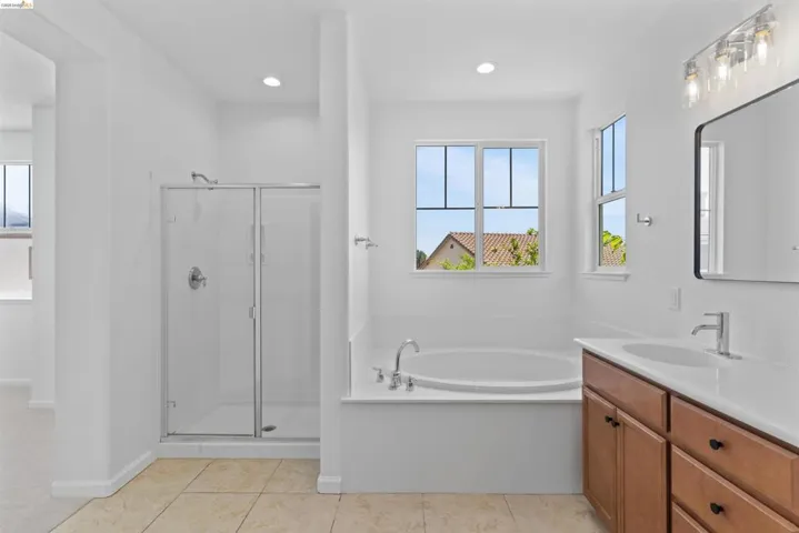 Bathroom featuring a built-in soaking tub, a clear glass shower enclosure, and a double vanity with wood-finish cabinetry