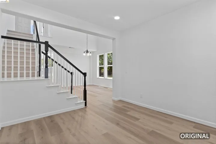 Interior space featuring wood-finish flooring and a staircase with white risers and dark wood handrails