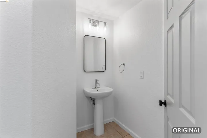 Pedestal sink featuring a polished chrome faucet, black-framed mirror, and a three-light vanity fixture