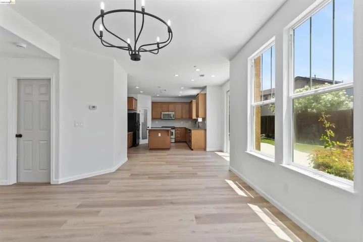 Open-concept living space featuring wood-finish flooring, a modern black chandelier, and multiple windows