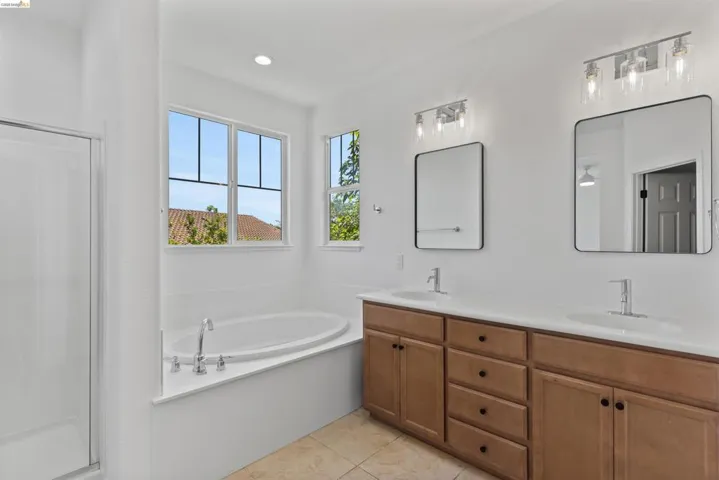 Spacious bathroom featuring a built-in soaking tub, separate shower enclosure, and a double vanity with ample counter space