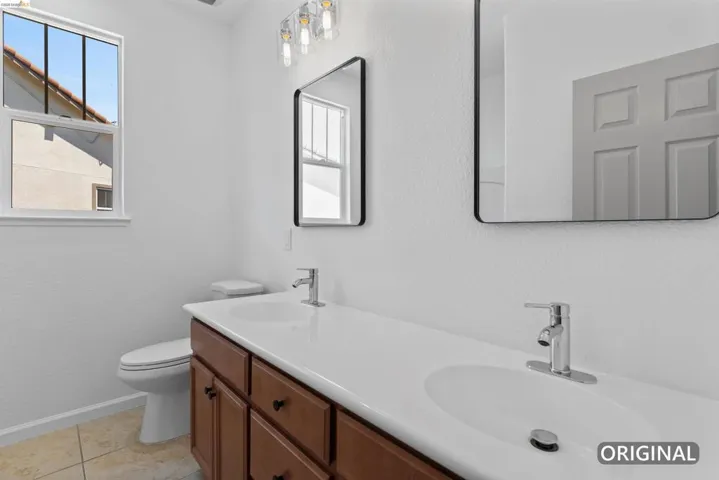 Double vanity with integrated sinks, wood-finish cabinetry, and chrome fixtures