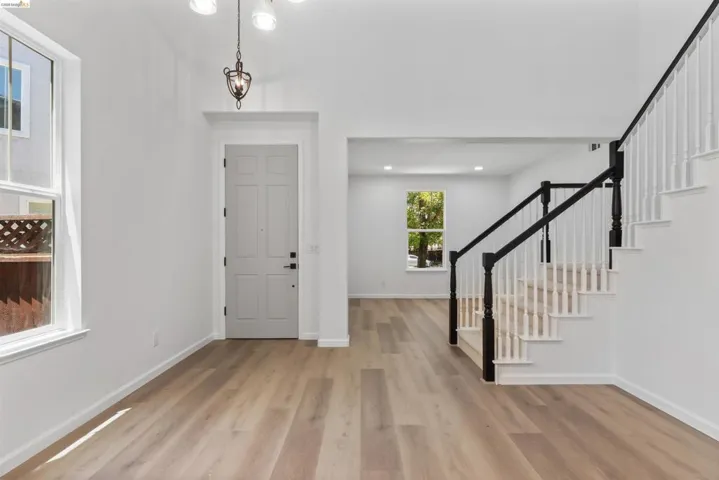 Vaulted entry featuring wood-finish flooring and a paneled front door