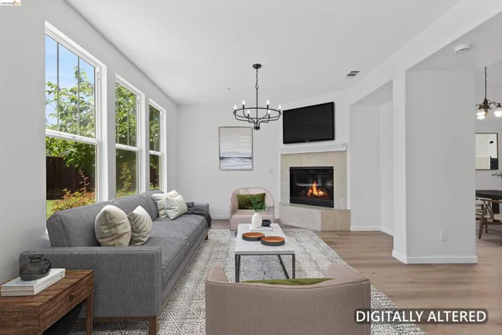 Living area featuring a corner fireplace with a stone surround, a chandelier, and multiple tall windows