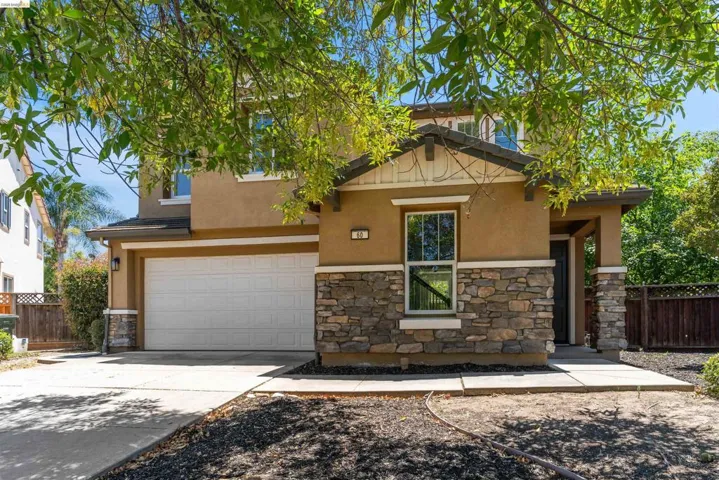Two-story stucco exterior featuring a stone facade accent, an integrated two-car garage, and a covered entry