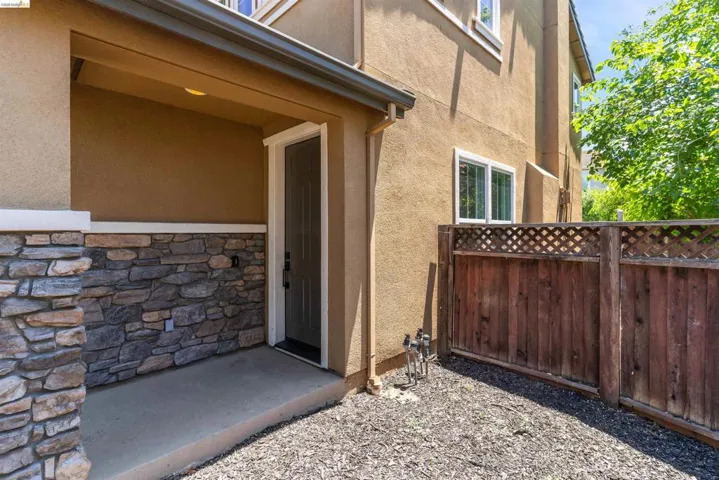 Covered entry featuring a stone veneer facade and stucco exterior