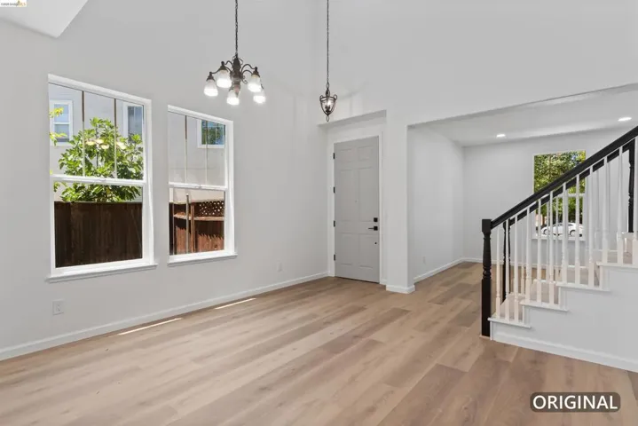 Expansive living area with vaulted ceilings, wood-finish flooring, and white walls