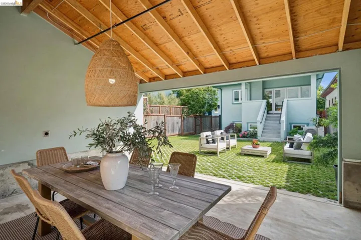 Covered patio with exposed wood ceiling beams and a large woven pendant light