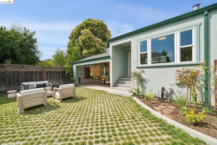 Rear exterior featuring a stucco finish with contrasting trim, a large picture window, and a planted border