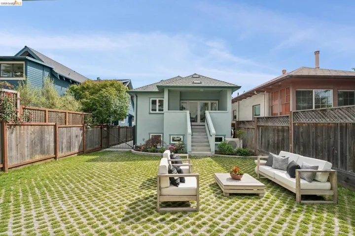 Rear exterior of the property featuring a light green facade and a partial-height wooden fence