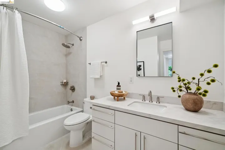 White vanity with a single undermount sink and brushed nickel faucet set, topped with a light-colored stone countertop