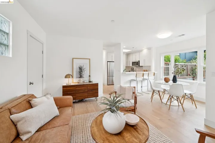Bright open-concept living area featuring light wood-finish flooring, recessed lighting, and a kitchen with stainless steel appliances