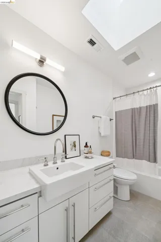 Bathroom featuring a white vanity with slab-front cabinetry, a rectangular vessel sink, and a chrome faucet