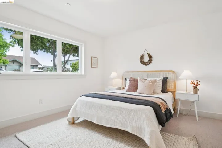 Light-filled room featuring a broad window, white walls, and carpet flooring