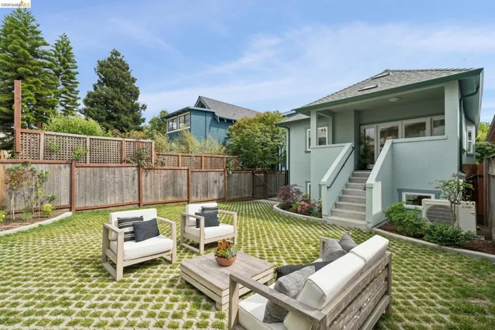 Expansive backyard featuring a grass paver patio, mature trees, and a wooden fence