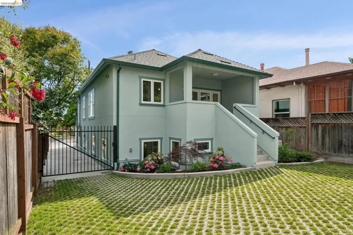 Rear exterior featuring a covered porch with stucco finish, accessible via exterior stairs with a handrail