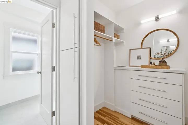 Built-in closet system featuring white cabinetry, shelving, and a dresser with a stone-finish countertop