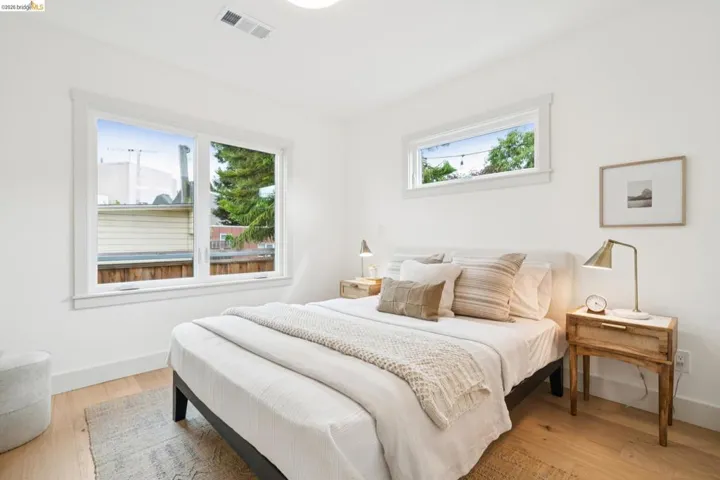 Bright bedroom featuring light wood-finish flooring, white walls, and a large double-pane window