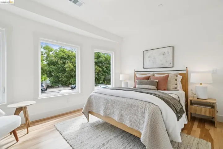 Bright bedroom featuring light wood-finish flooring and multiple windows