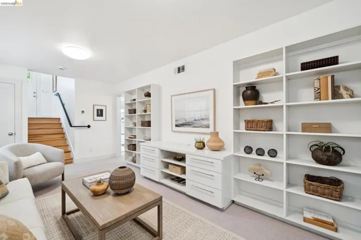 Living area featuring built-in shelving, wood flooring on staircase, neutral wall paint, and recessed lighting
