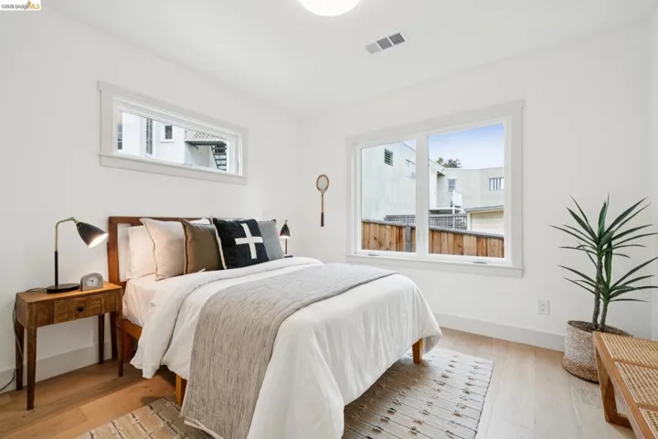 Bright room featuring two distinct windows, wood-finish flooring, a built-in ceiling light, and white baseboards