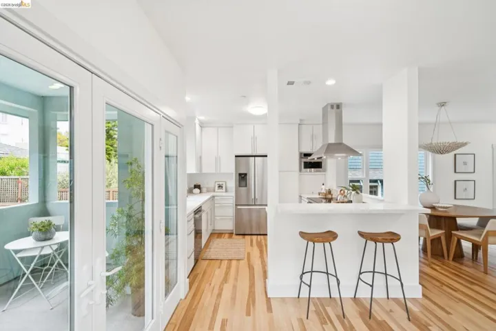 Bright kitchen featuring white cabinetry, stainless steel appliances, a breakfast bar, and wood-finish flooring