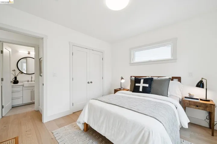 Bright bedroom with light wood-finish flooring, white walls, and a horizontal window