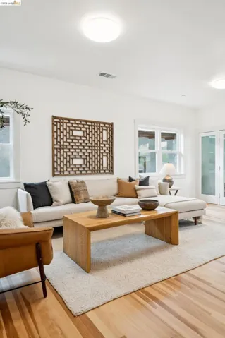 Bright living space featuring natural wood-finish flooring, white walls, multiple windows, and recessed lighting
