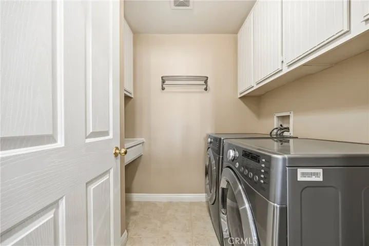 Convenient laundry room with a modern washer, dryer, and ample cabinet storage