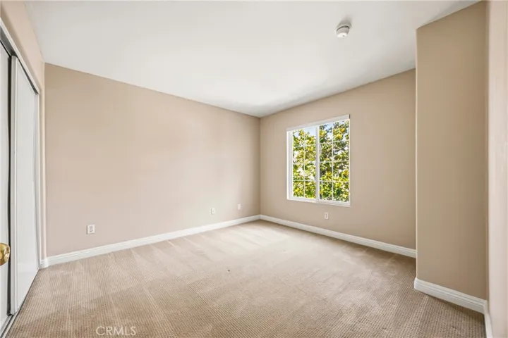 Bright second bedroom with a peaceful tree-lined window view
