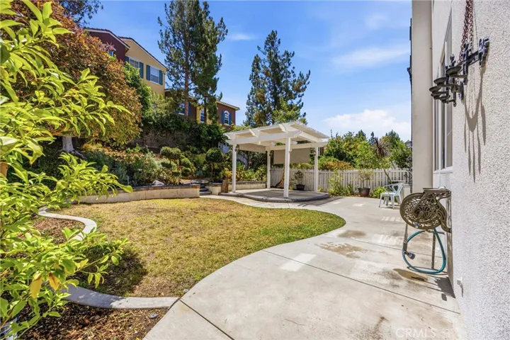 Spacious backyard with a charming white pergola and patio area