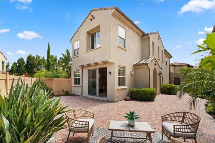 Rear exterior showcasing sliding glass door access and a low maintenance backyard with paver patio.