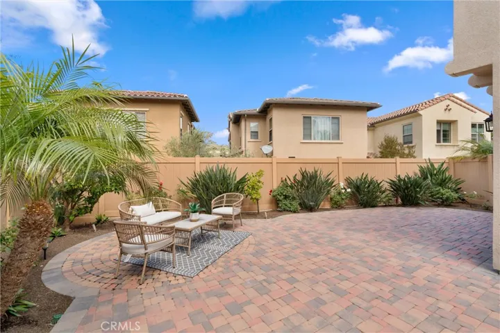 Private backyard featuring expansive paver hardscape, landscaped planting beds, and flexible outdoor living space.