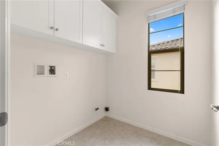 Dedicated upstairs laundry room with upper storage cabinetry and natural light.