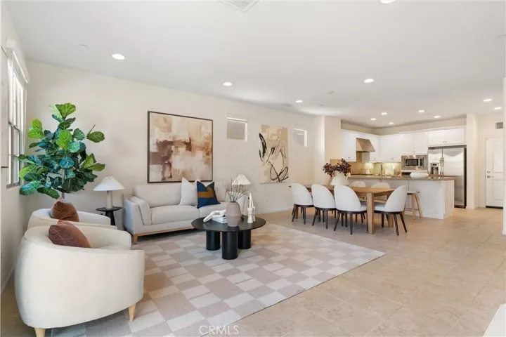 Open concept living, dining, and kitchen layout with tile flooring, recessed lighting, and connected gathering spaces.