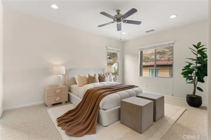 Spacious primary suite featuring recessed lighting, plush carpeting, and large windows that bring in natural light and hillside outlooks.