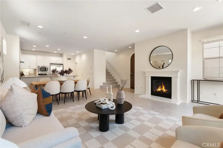 Main living area featuring a fireplace, recessed lighting, and an open layout connecting to the dining area and kitchen.
