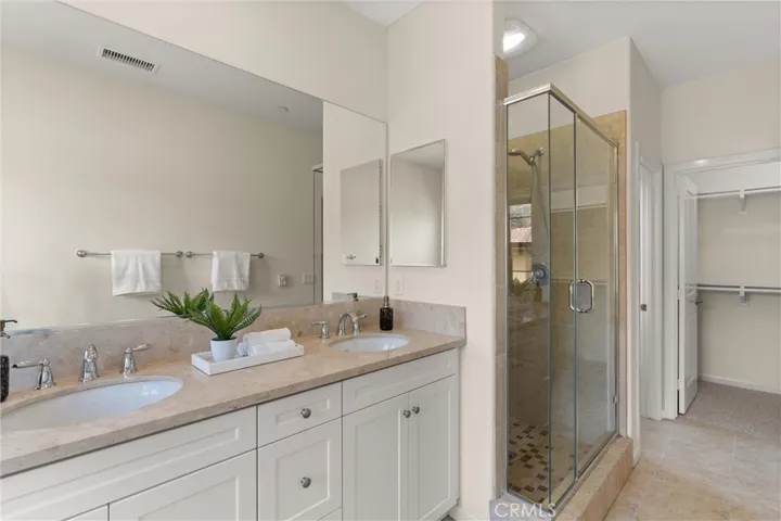 Well appointed primary bathroom offering separate shower, dual vanities, and direct access to the walk in closet.