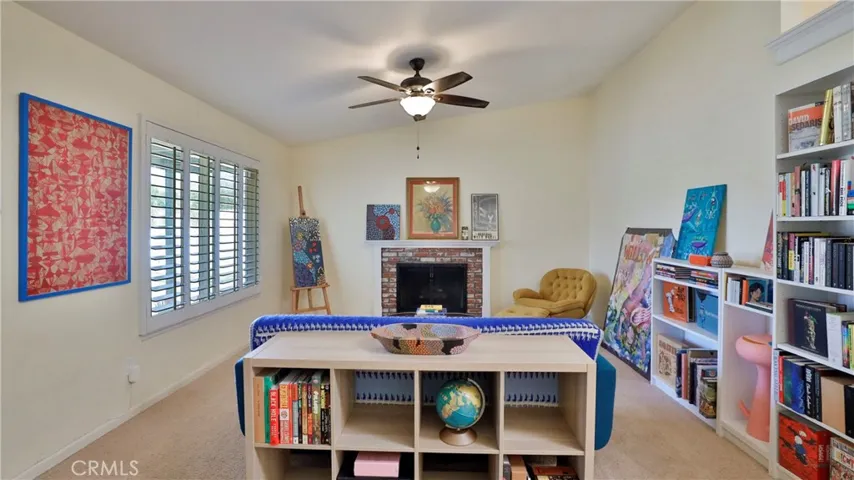 Living room: plantation shutters, ceiling fan with vaulted ceiling, ceramic tiled flooring and a wood/gas burning stove