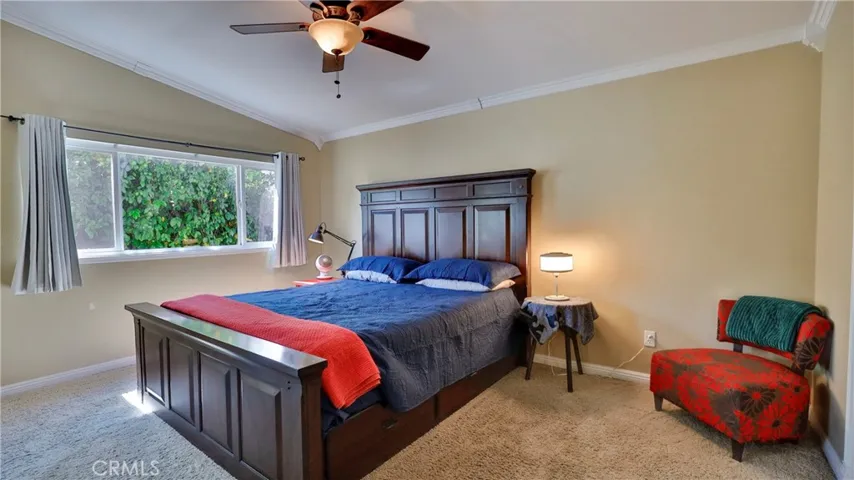 Primary bedroom features: carpet, ceiling fan, large window, crown molding