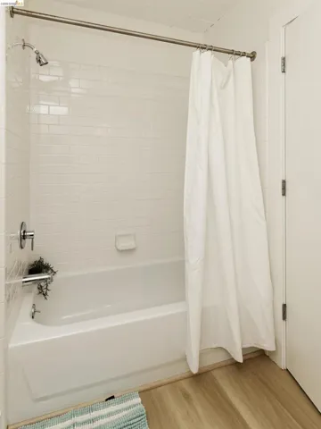 Bathroom with shower / bath combo and light wood-style flooring
