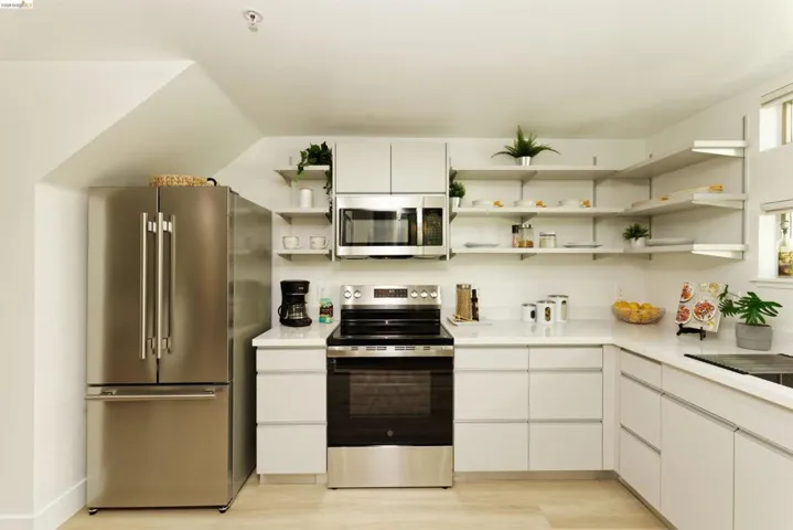 Kitchen with appliances with stainless steel finishes, white cabinets, and modern cabinets