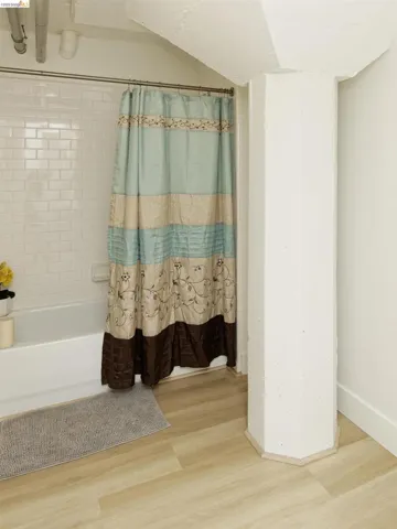 Full bath with shower / bath combo and wood finished floors