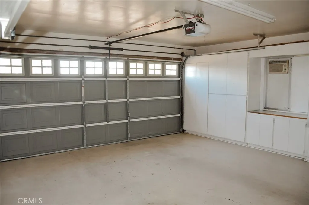 Garage has built in cabinets and workspace.