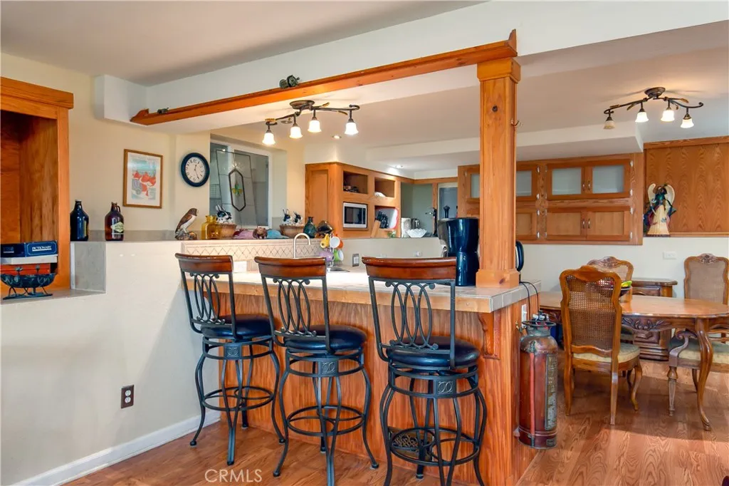 A dedicated kitchen space located within the private lower-level suite. This functional setup offers extensive oak upper and lower cabinets for storage, clean countertops, integrated appliances, and a raised breakfast bar ledge that opens directly to the dining area, providing a completely independent living experience.