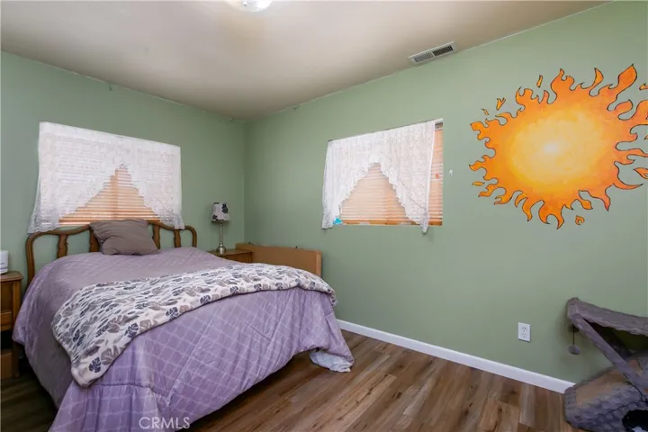 The inviting second bedroom located upstairs right next to the hallway bathroom. This versatile room features a clean neutral color palette, white baseboards, and a large window with blinds that fills the space with great natural light, making it a perfect kid's room, guest room, or home office.